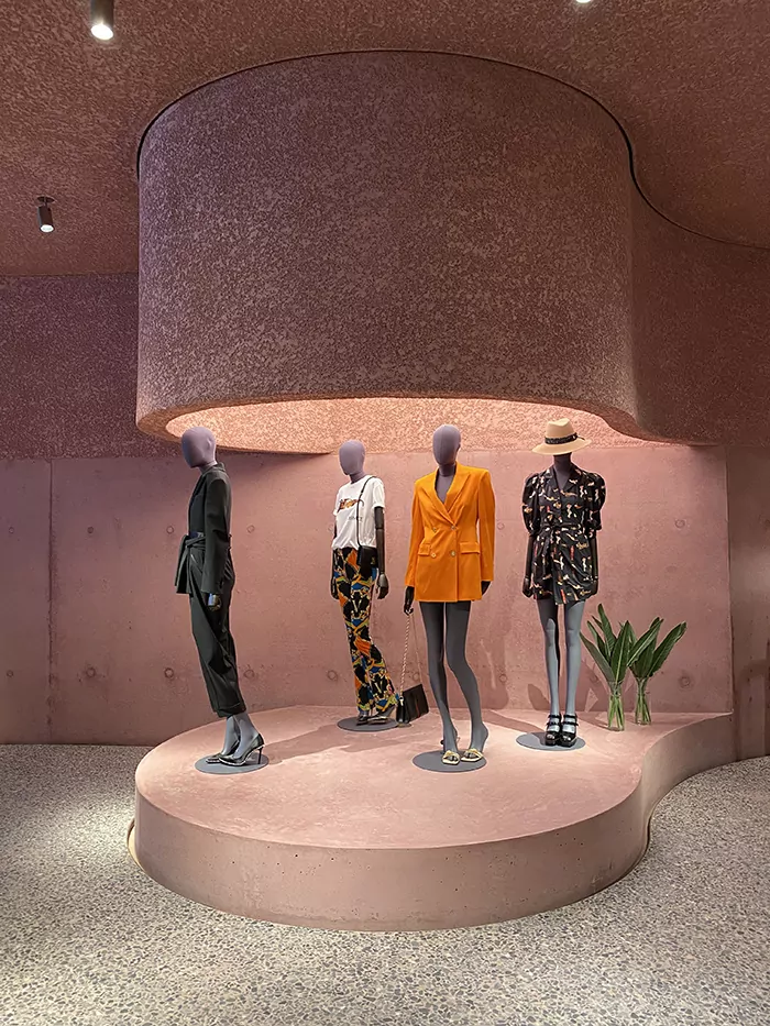Acoustement acoustical plaster pigmented pink and spray applied to walls and ceiling of a fashion store