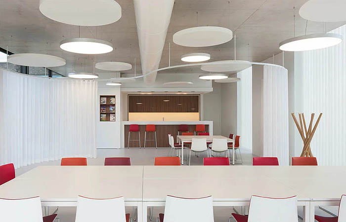 white circular acoustical perforated metal ceiling clouds suspended in an office kitchen dining area