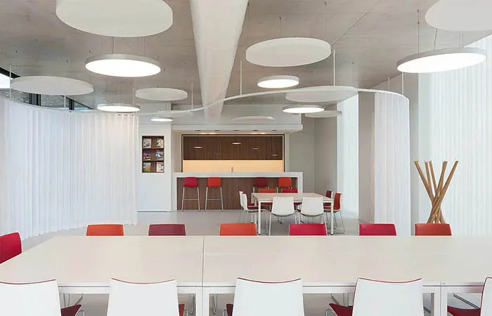 white circular acoustical perforated metal ceiling clouds suspended in an office kitchen dining area