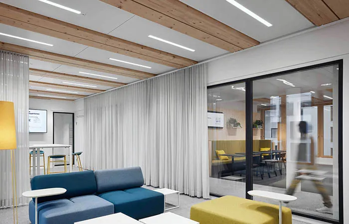 metal ceiling rafts installed between mass timber beams with linear integrated light fixtures.