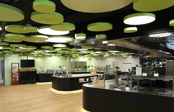 vibrant green circular metal ceiling clouds with circular light fixtures in a cafeteria dining area