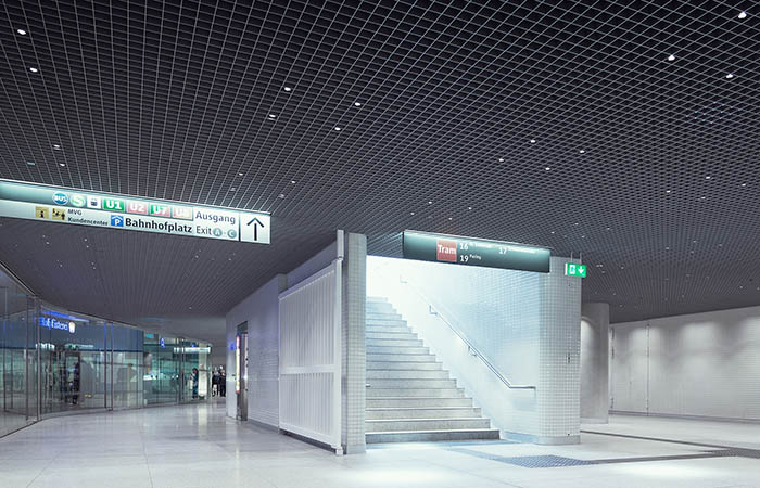 Square metal open cell ceiling with point light integrations in a train station.