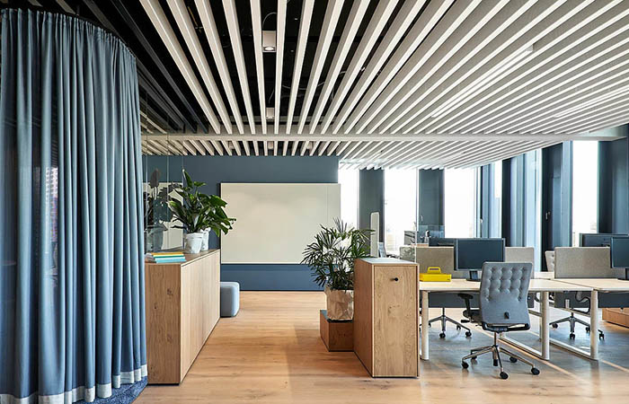 Linear metal perforated acoustical baffles in white and black in an open office.