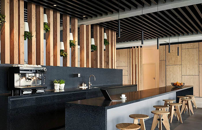 Black perforated metal linear acosutical baffles above an office kitchen area.