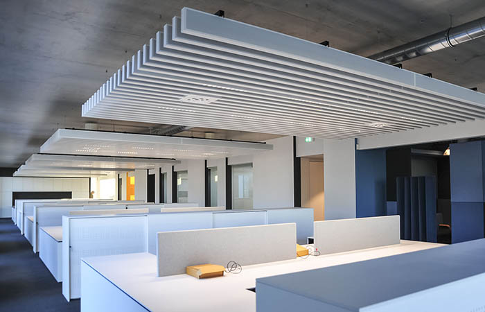 Clustered acoustical linear metal baffles above office cubicles in an open office environment.