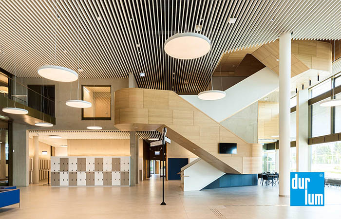 White acoustical polylam metal linear baffle ceiling in a building lobby.