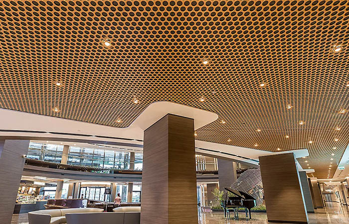 loop open cell metal ceiling in bronze powdercoat with downlights in hotel circulation