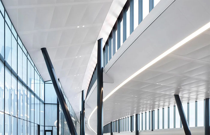 White metal perforated ceiling panels for sound absorption and speech intelligibility in an airport terminal