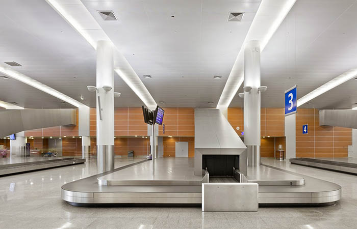 Perforated metal ceiling panels above baggage claim in an airport terminal