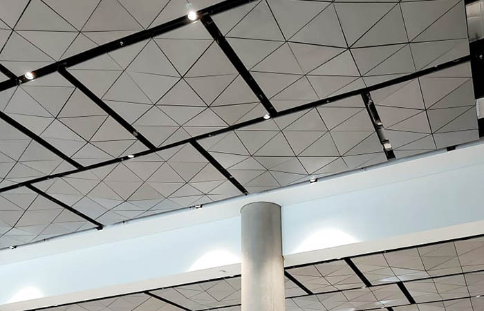 Metal acoustic ceiling panels in a triangular pattern with gray powder coated finish.
