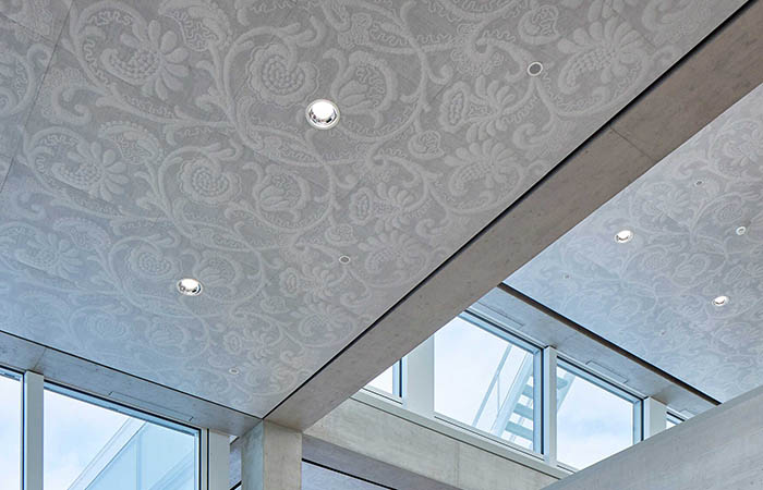 Perforated metal ceiling panels with a powdercoated printed lace texture and graphic