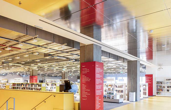 Reflective perforated ceiling panels for sound absorption and daylight management.