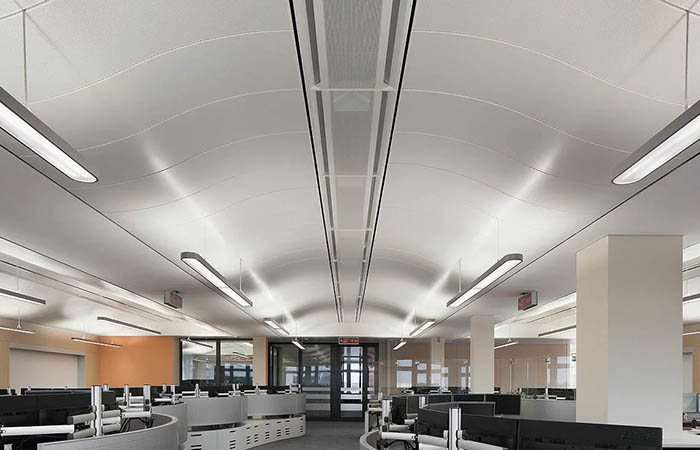 Curved perforated metal ceilings in an open plan office.